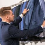 Un homme fait le choix de ses costumes pour l'hiver dans un magasin de vêtement.