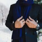 Un homme ajuste avec élégance, son écharpe sur son costume en plein hiver.