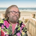 Le chanteur Antoine en chemises hawaïennes sur une plage, continue de faire parler son style.